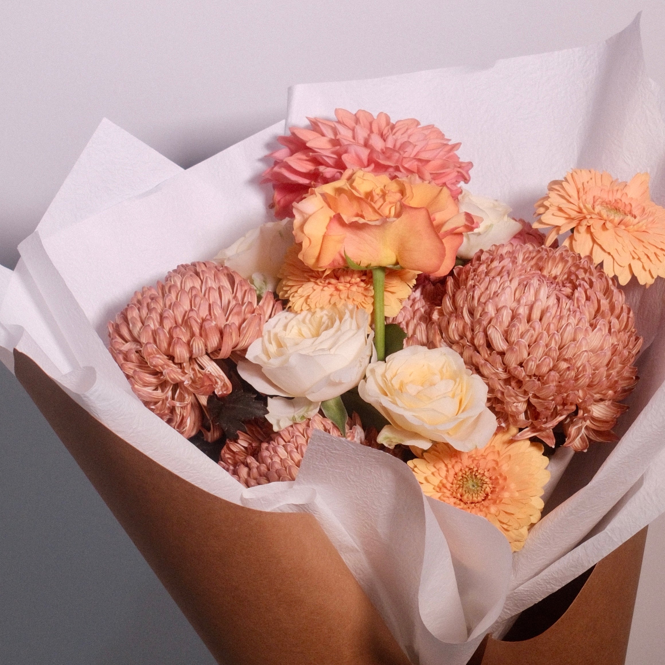 Bouquet of brown and yellow rose flowers wrapped in brown paper with a white ribbon. Designed for brown gown for university graduation ceremonies, perfect graduation gift by Hanaya Flora, based in Sydney.