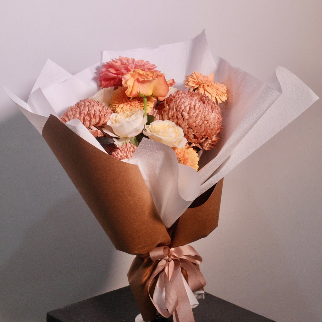 Bouquet of brown and yellow rose flowers wrapped in brown paper with a white ribbon. Designed for brown gown for university graduation ceremonies, perfect graduation gift by Hanaya Flora, based in Sydney.