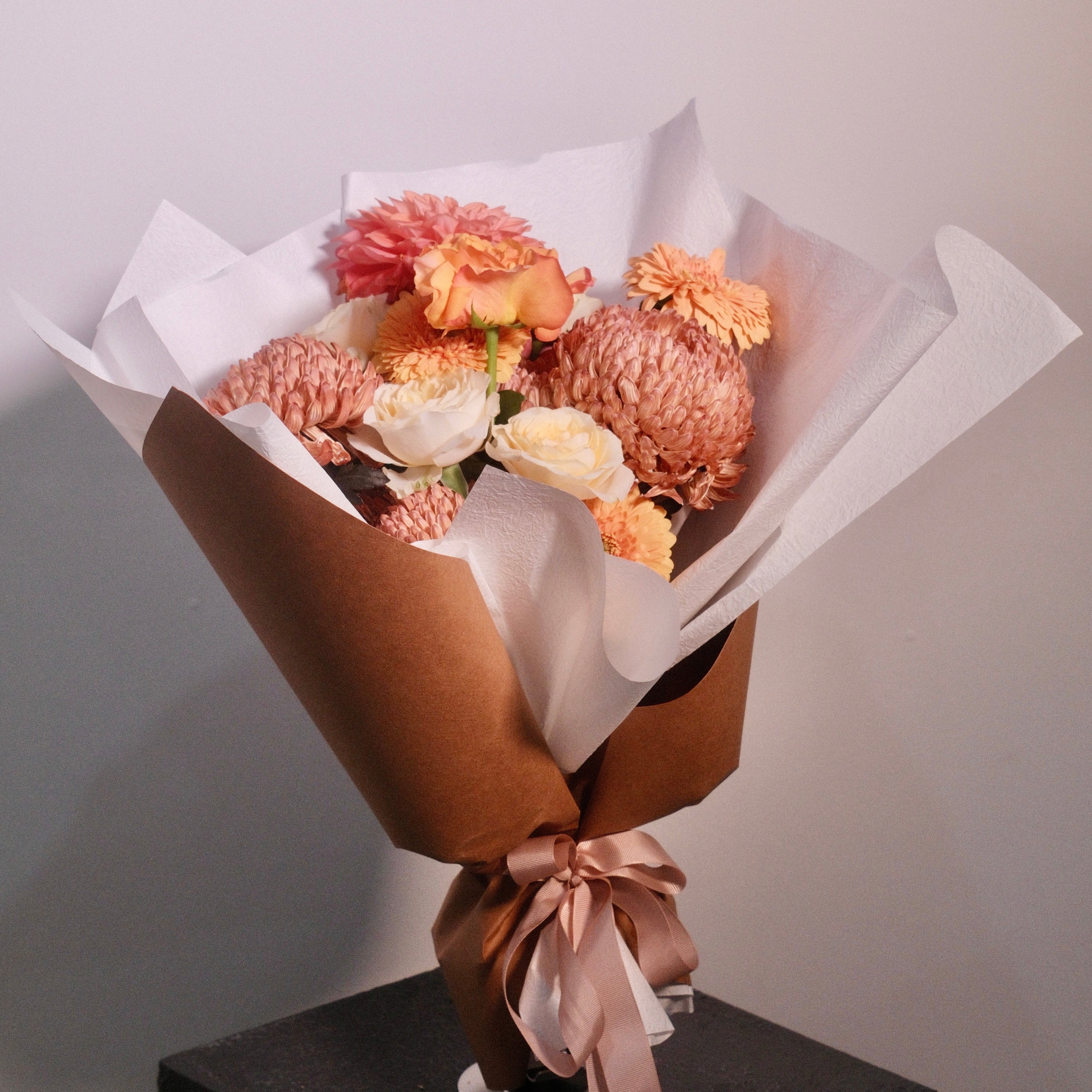 Bouquet of brown and yellow rose flowers wrapped in brown paper with a white ribbon. Designed for brown gown for university graduation ceremonies, perfect graduation gift by Hanaya Flora, based in Sydney.