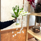 Cascading white hyacinth bridal bouquet with hanging crystal beads, styled against a textured wall