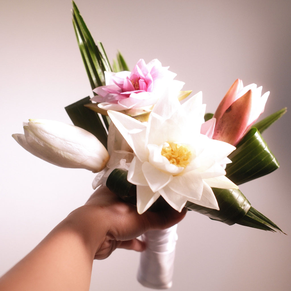 Bridal bouquet with white and pink lotus flowers and tropical leaves