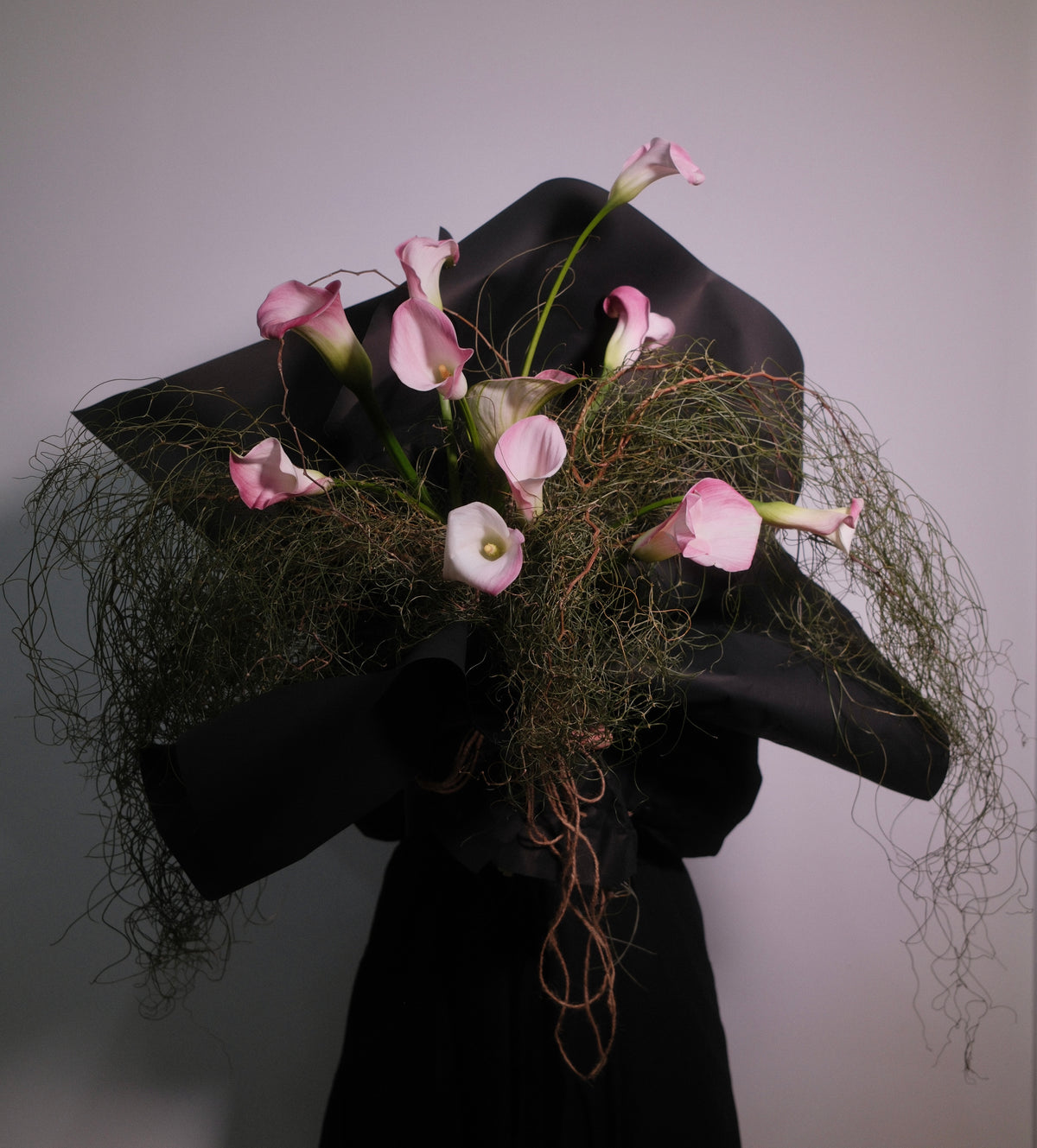 Flower bouquet of wild flowers arranged with calla lilies wrapped in black paper, 