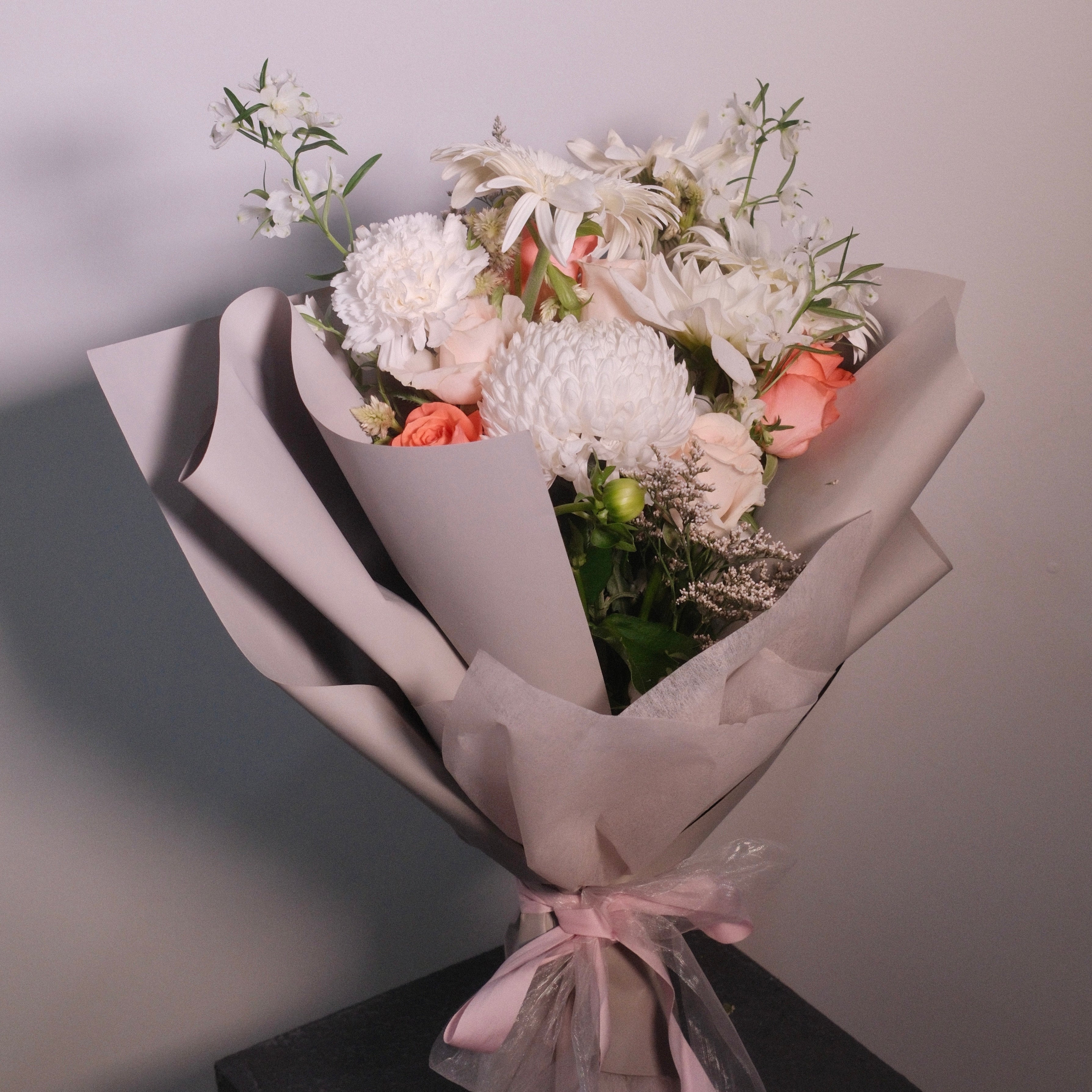 Bouquet of elegant white flowers wrapped in brown paper with a pink ribbon by Hanaya Flora, Sydney. Perfect flowers for mum gift and flowers ideas.