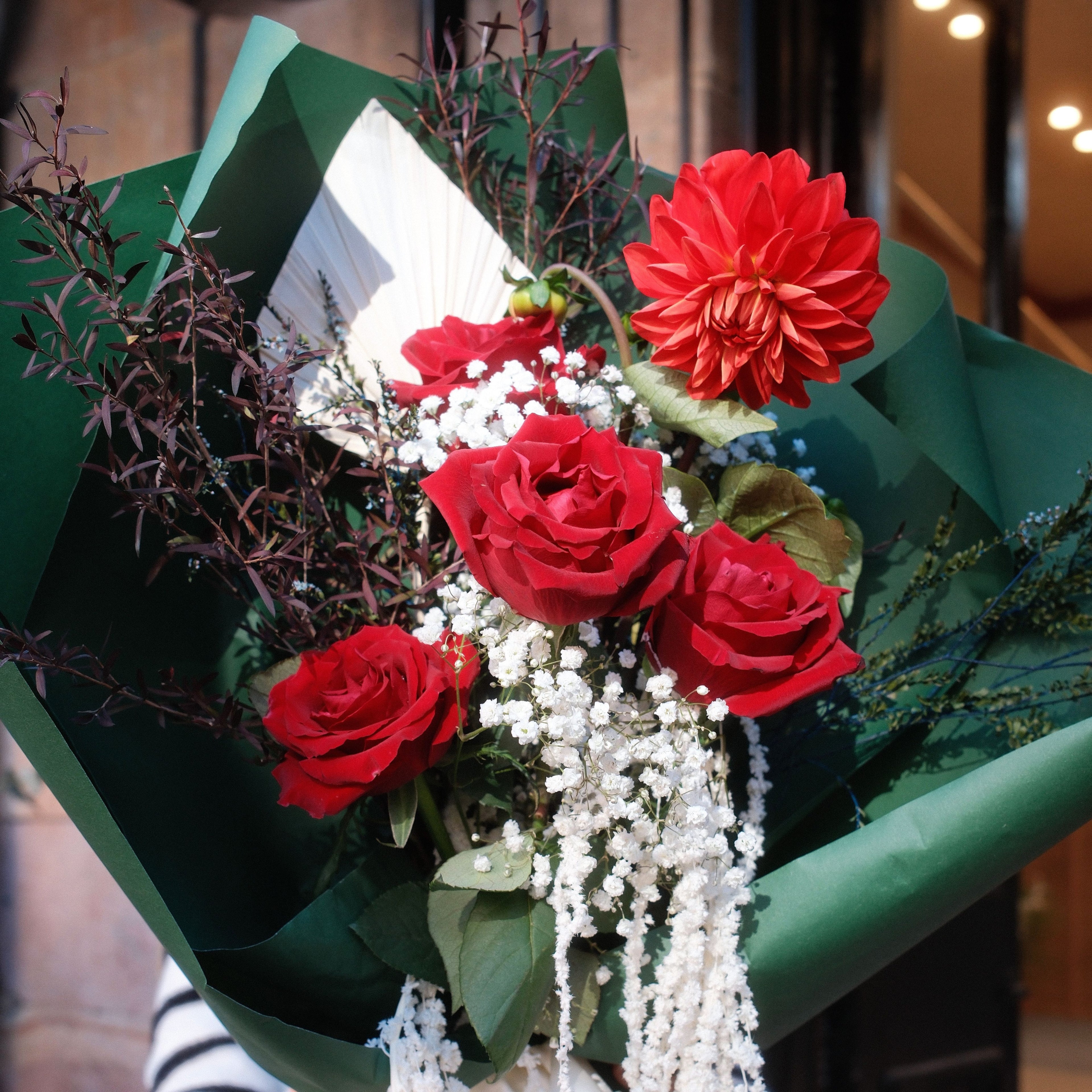 Close-up of red roses and dahlia in the Crimson Cascade bouquet by Hanaya Flora