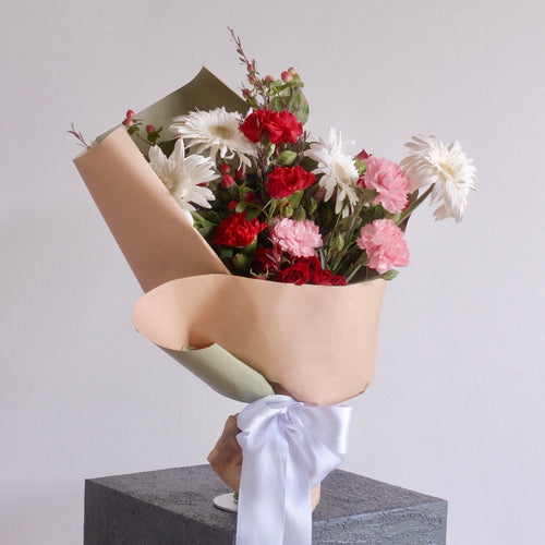 Bouquet of flowers wrapped in green paper with a white ribbon, red rose, red flower, gerbera by Hanaya Flora, Sydney, Surry Hills.