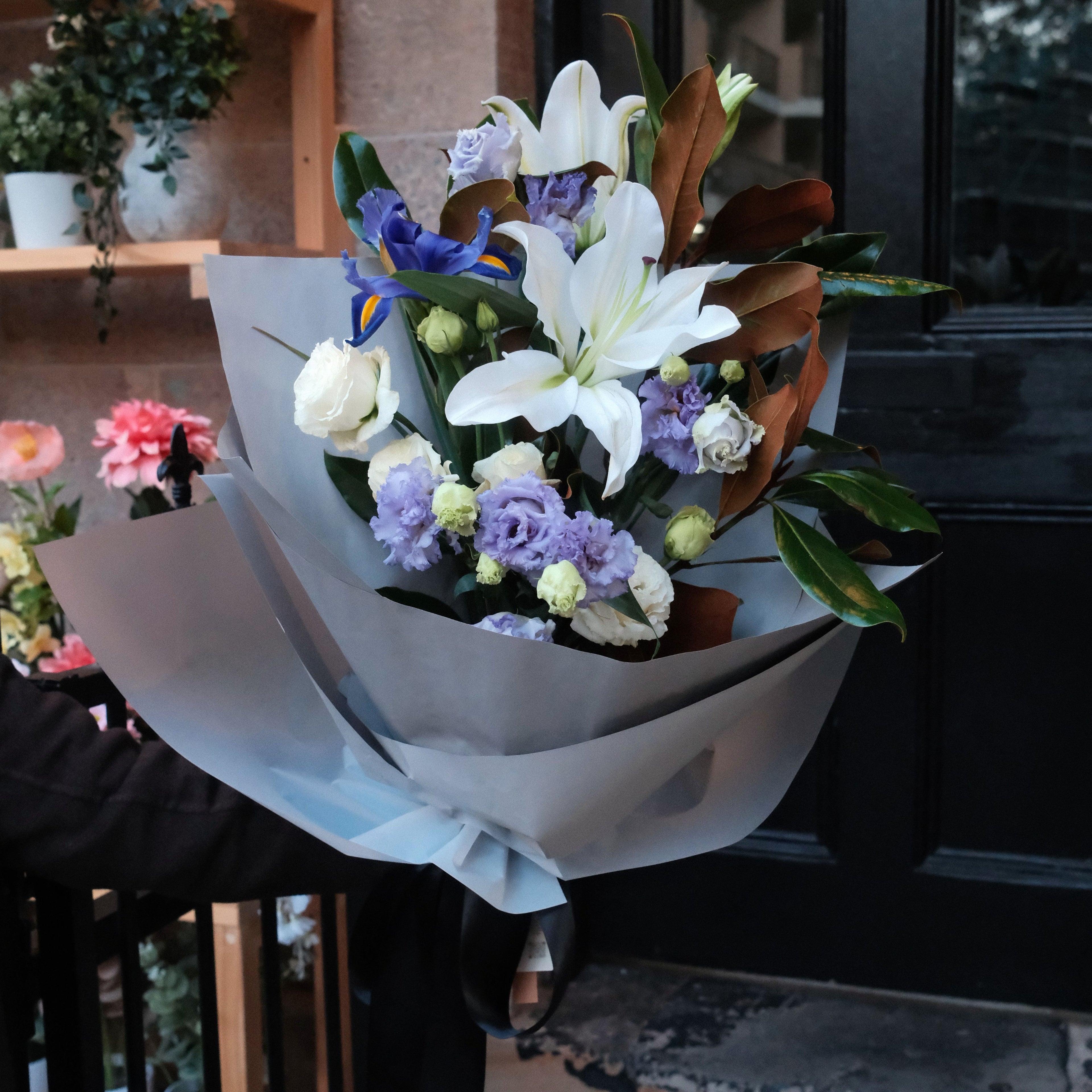 Close-up of Gentle Farewell bouquet featuring white lilies, blue iris and copper magnolia foliage, Hanaya Flora Surry Hills