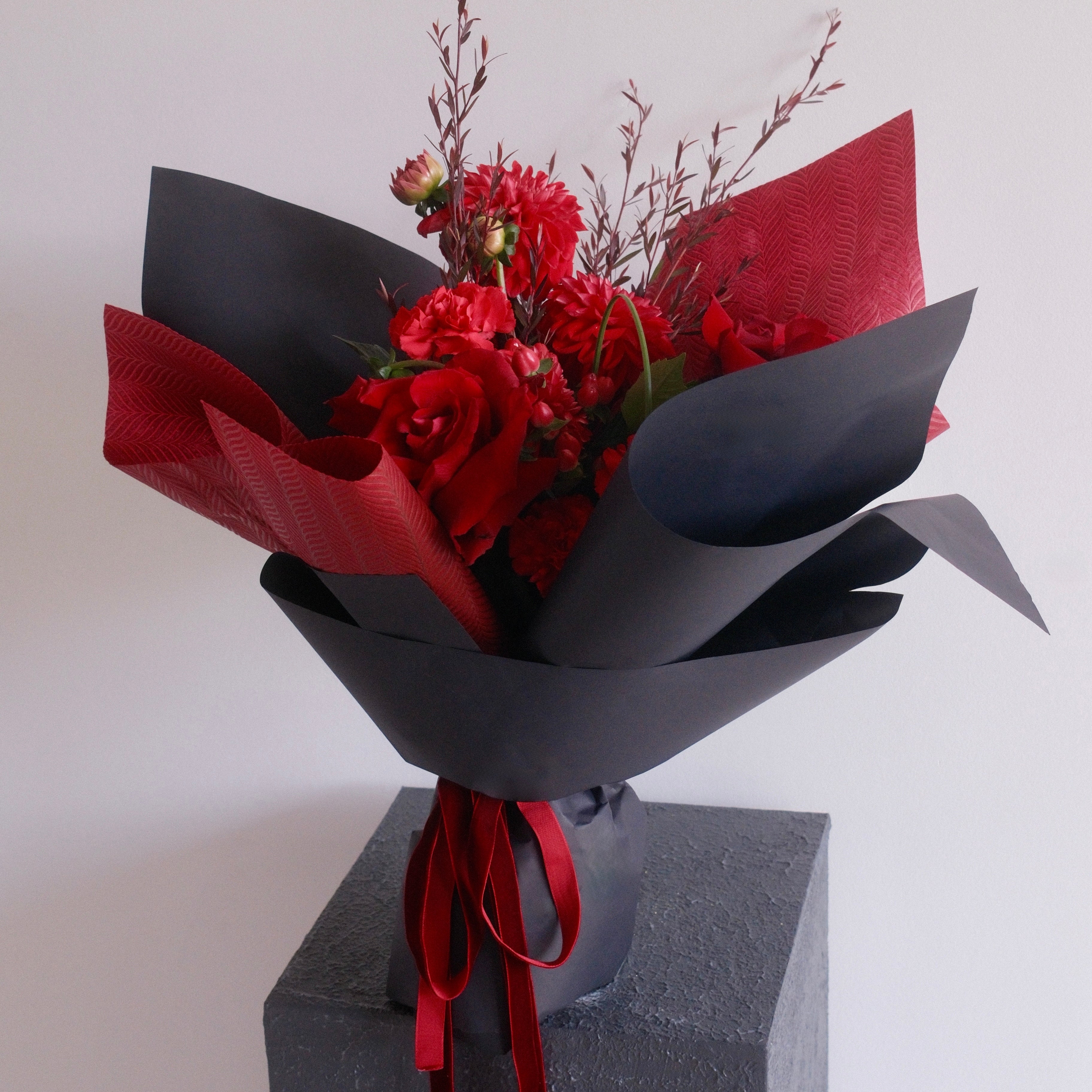 Bouquet of red flowers wrapped in black paper with a red ribbon, perfect for graduation gift ideas made by Hanaya Flora, based in Sydney.