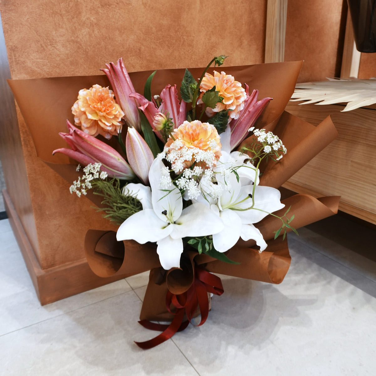 Hana-Akari bouquet of white and pink Oriental lilies, peach dahlias and Queen Anne's lace in caramel wrapping with a burgundy ribbon