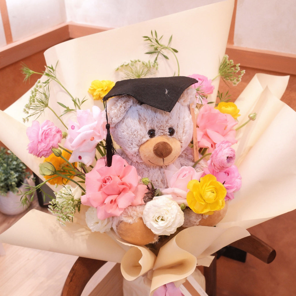 Kuma Joy graduation bouquet with pink roses, yellow blooms and a graduation teddy bear