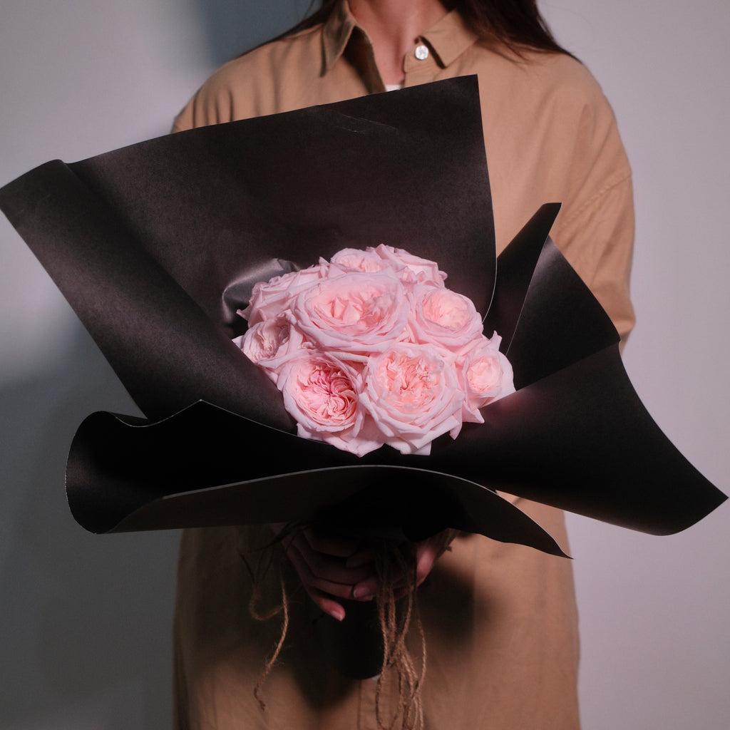 Florist holding the Midnight Bloom blush rose bouquet in a black architectural wrap, Sydney