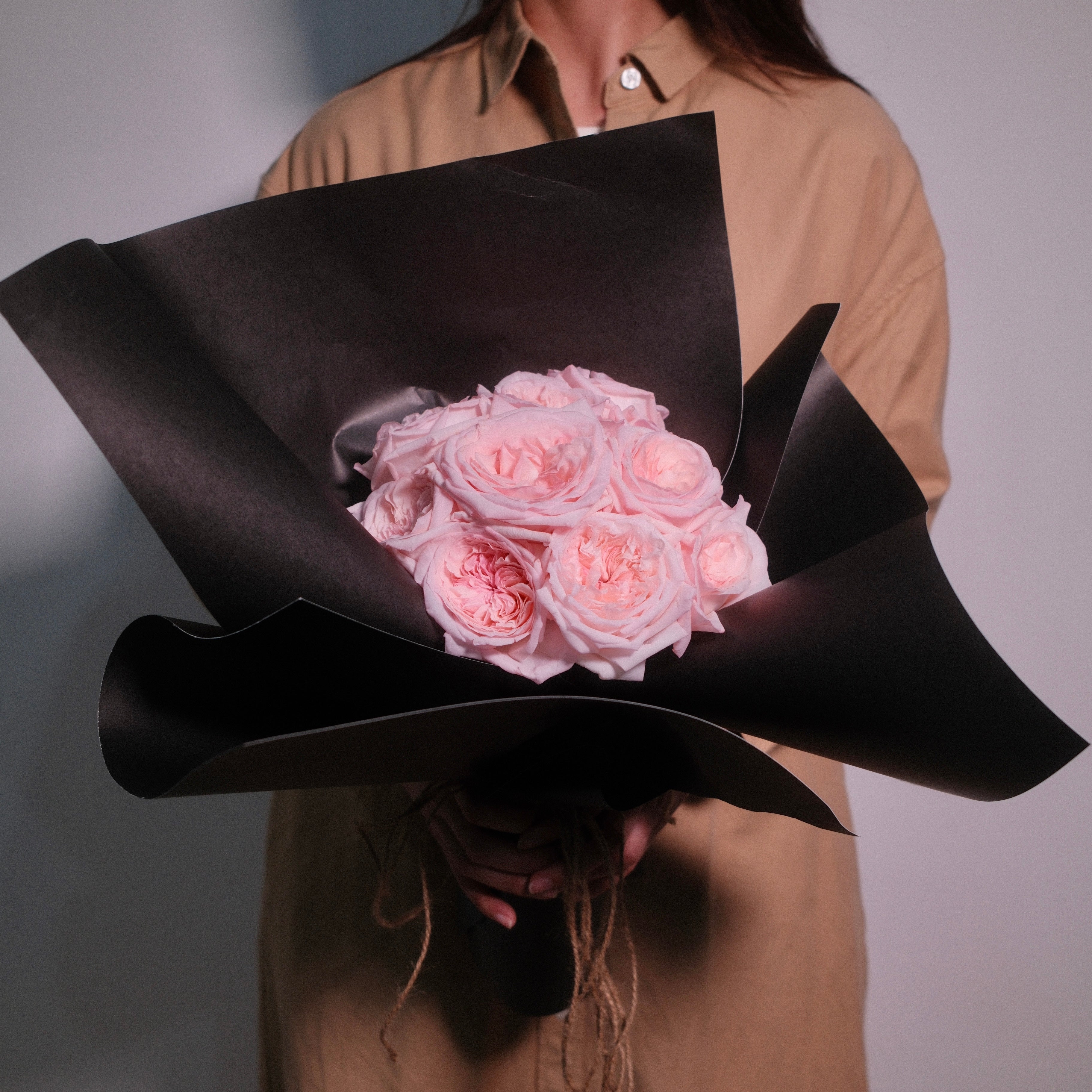 Florist holding the Midnight Bloom blush rose bouquet in a black architectural wrap, Sydney