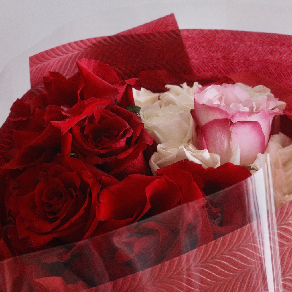 Close-up of Mika Harmony bouquet with red and blush blooms in signature wrap