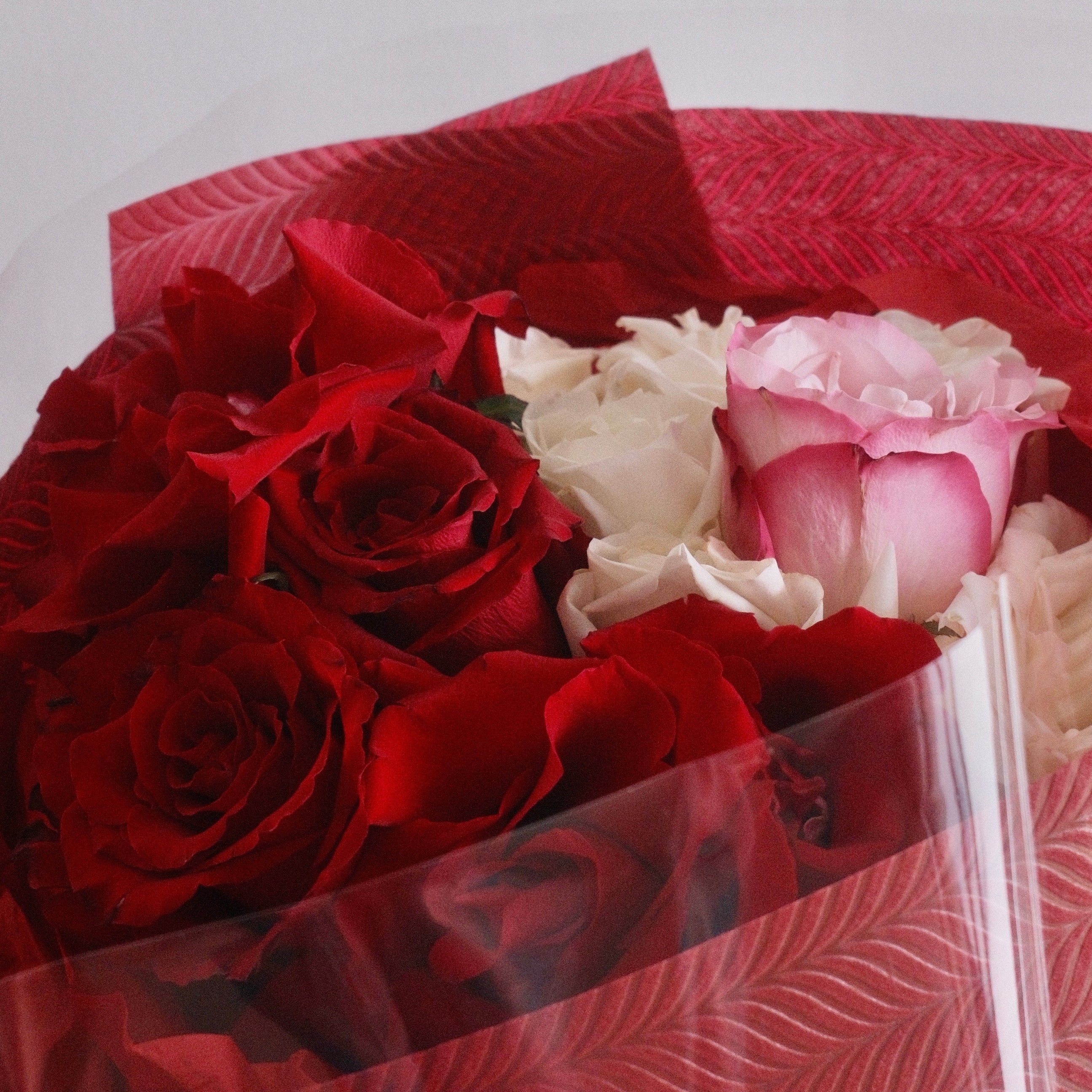 Close-up of Mika Harmony bouquet with red and blush blooms in signature wrap