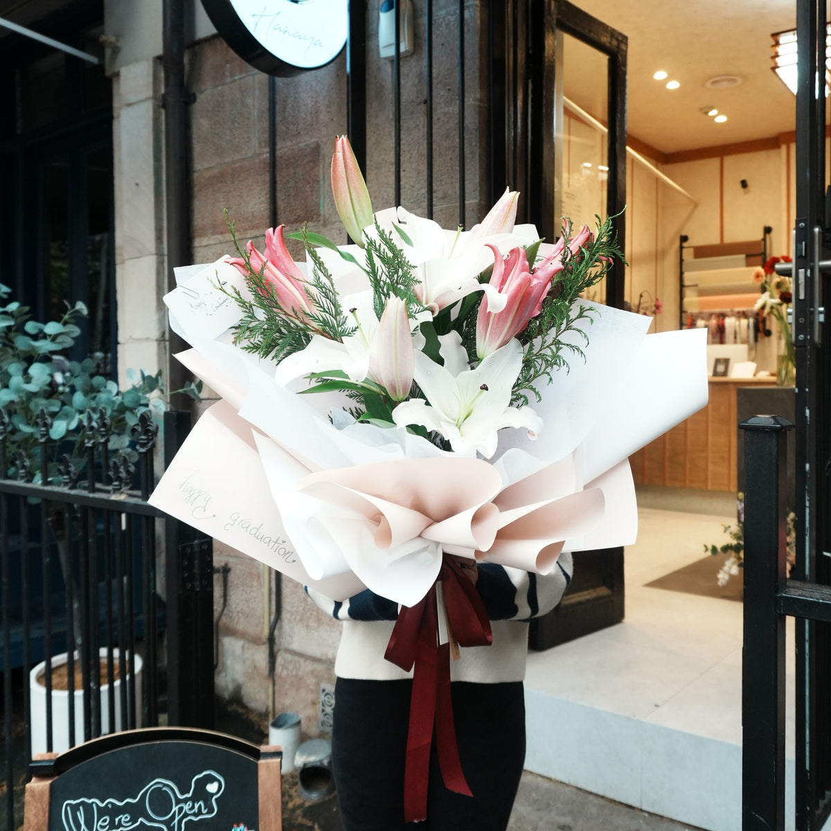 Person holding the Mirai Grace lily graduation bouquet outside Hanaya Flora florist in Sydney