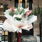 Mirai Grace pink and white lily graduation bouquet with "happy graduation" wrapping, outside a Sydney sandstone shopfront