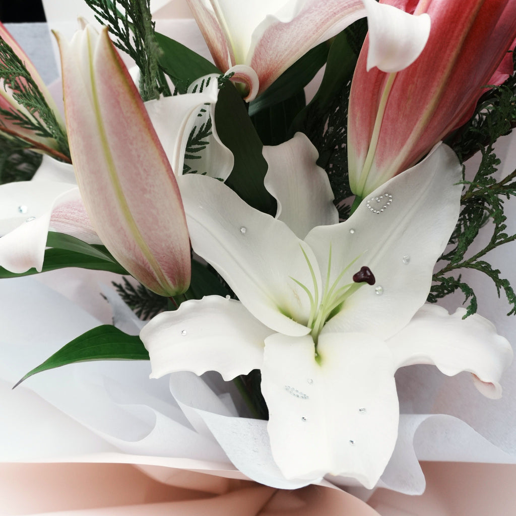 Close-up of a white Oriental lily in the Mirai Grace bouquet, decorated with crystal gems and a sparkling heart