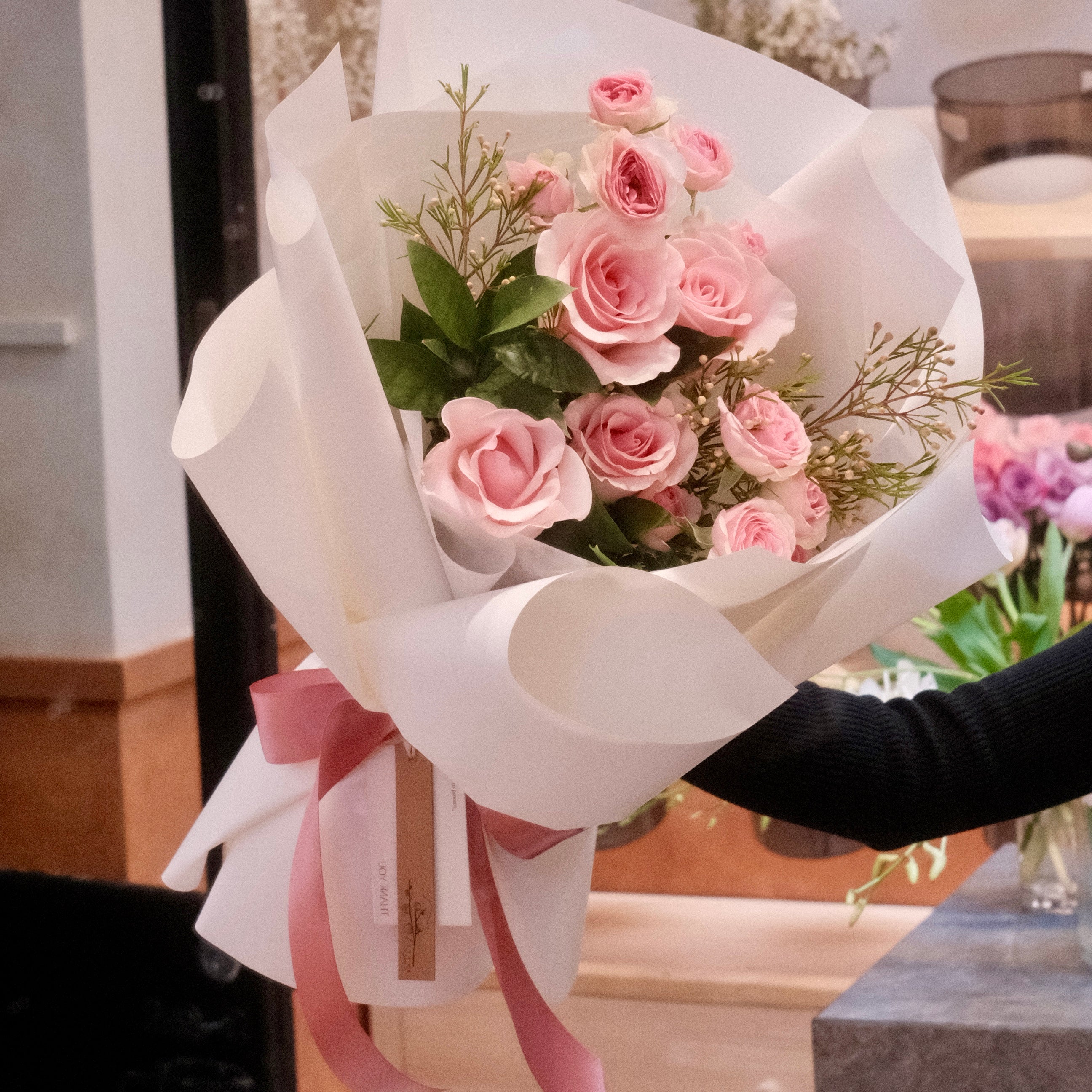 Florist holding the Momoiro pink rose bouquet, a June birthday flower gift