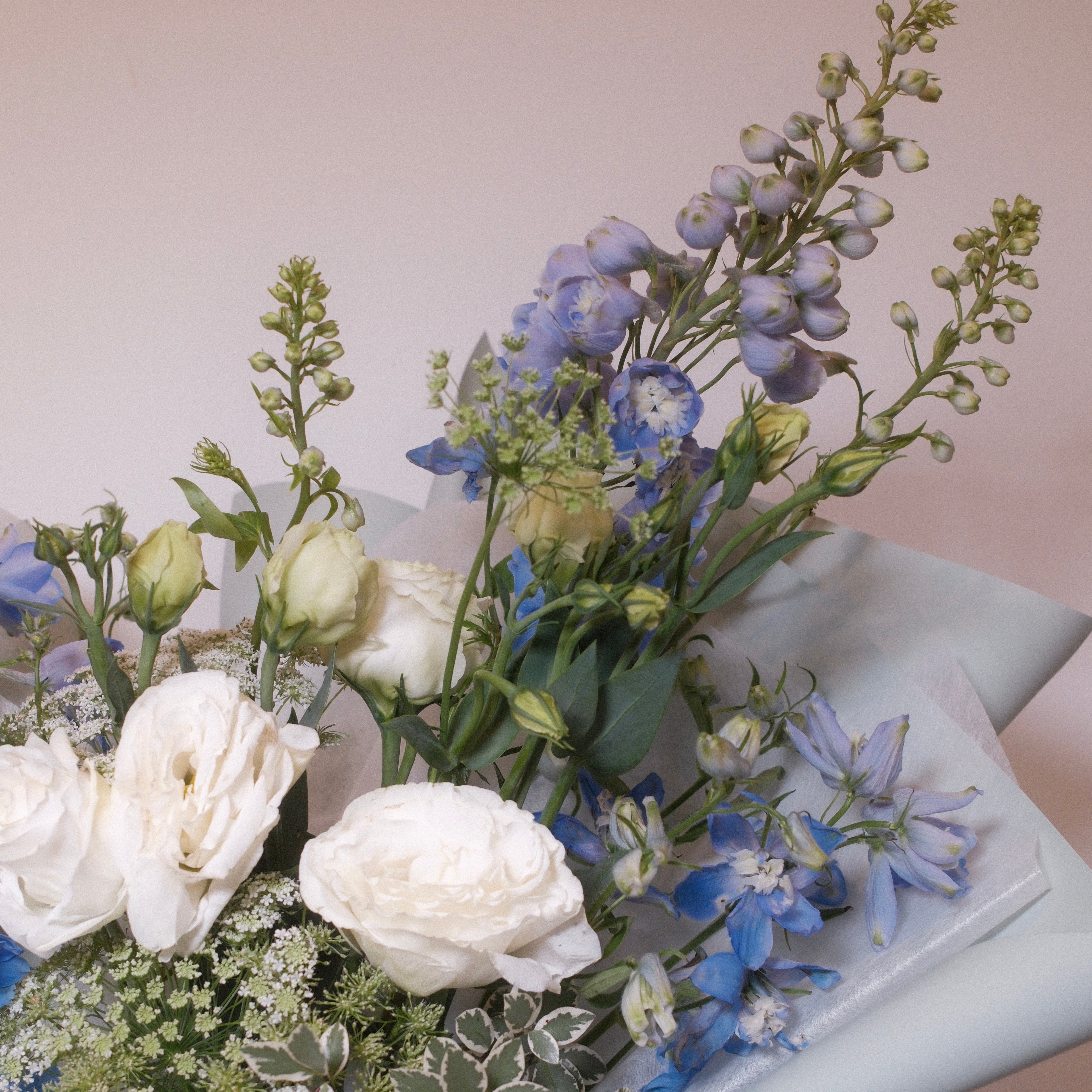 Close-up of blue delphinium and white lisianthus in the Natsuzora bouquet