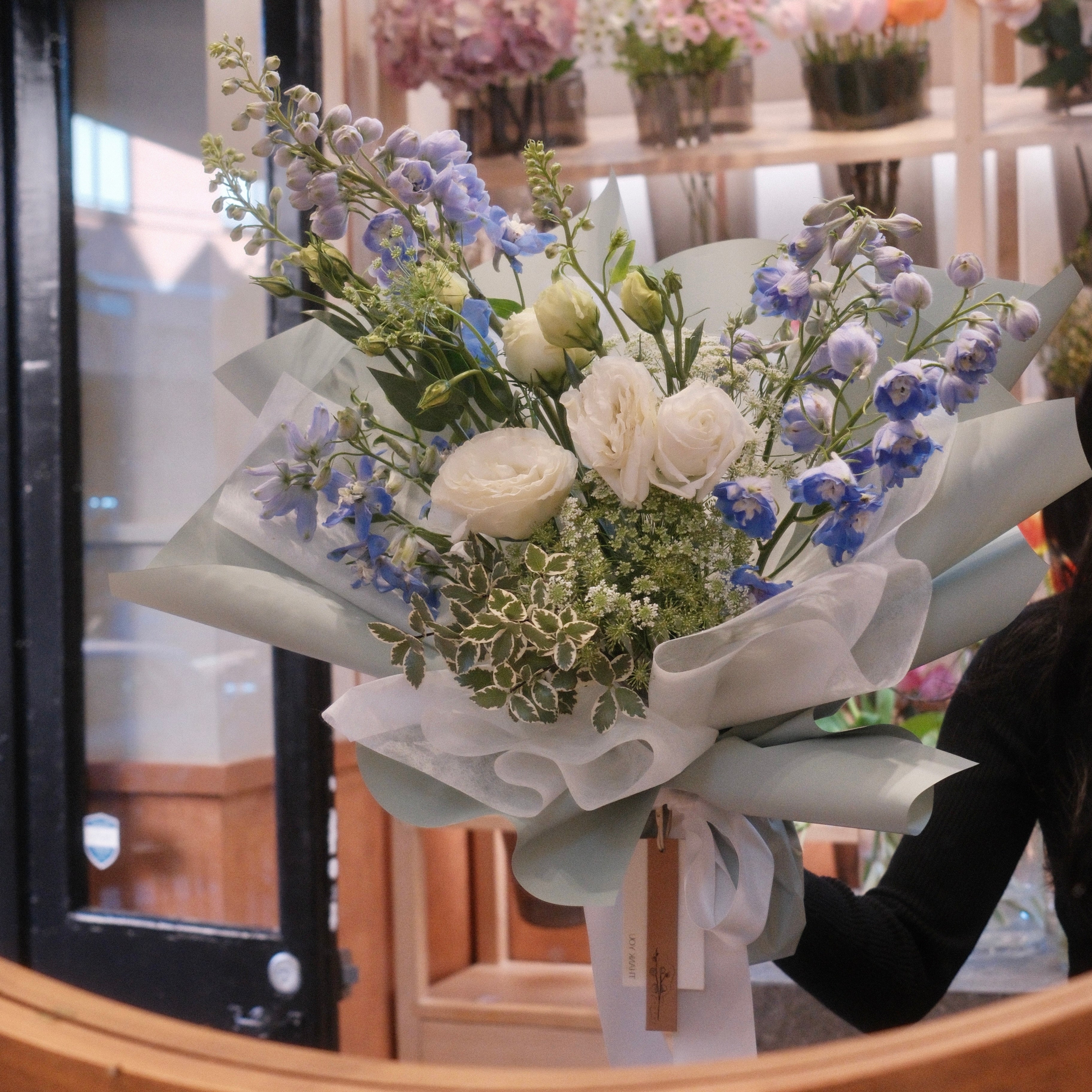 Florist holding the Natsuzora delphinium bouquet, a July birthday flower gift