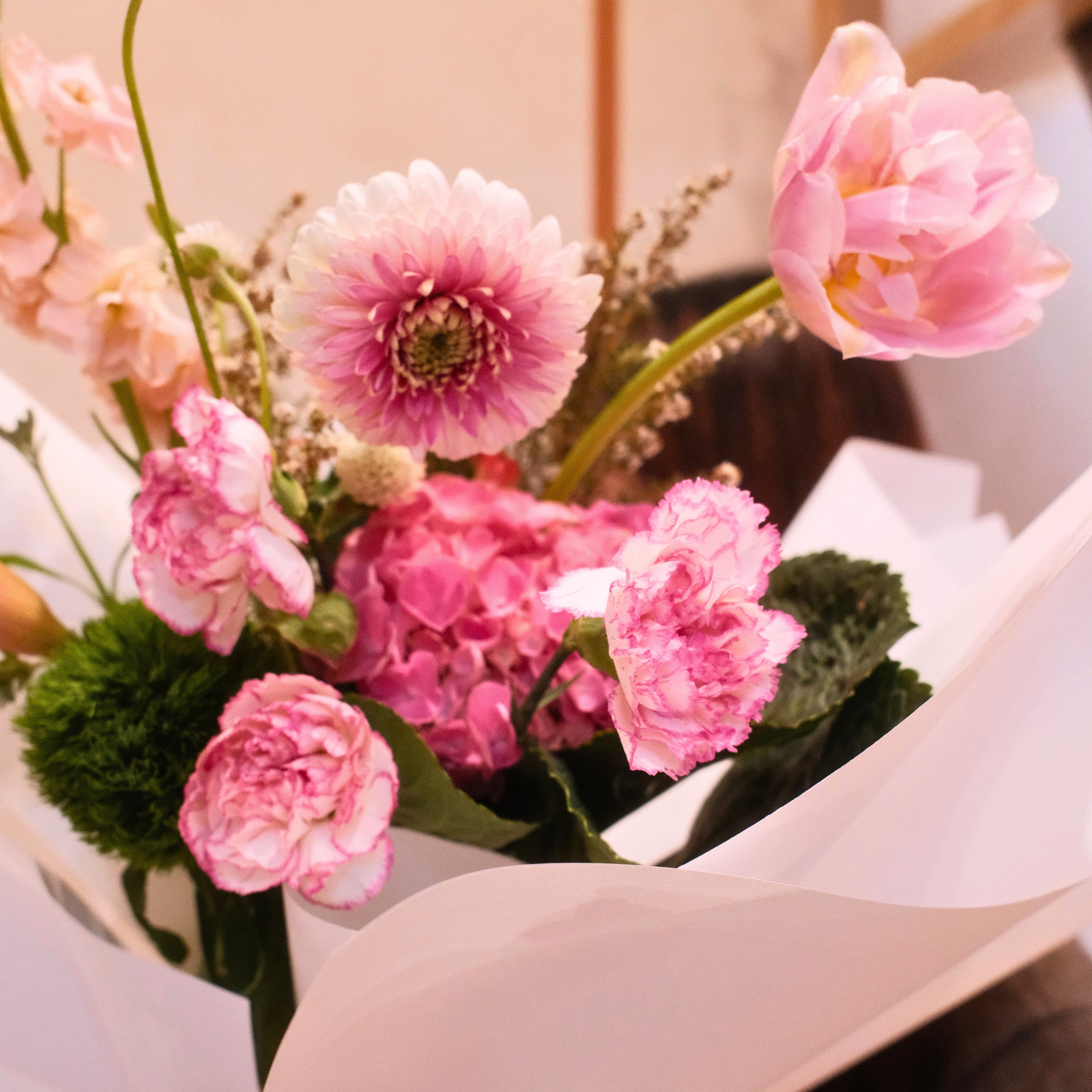 Bouquet of mixed pink flowers with tulip, calla lily, gerbera, hydrangea wrapped in white paper with a red ribbon made by Hanaya Flora, Surry Hills, Sydney.