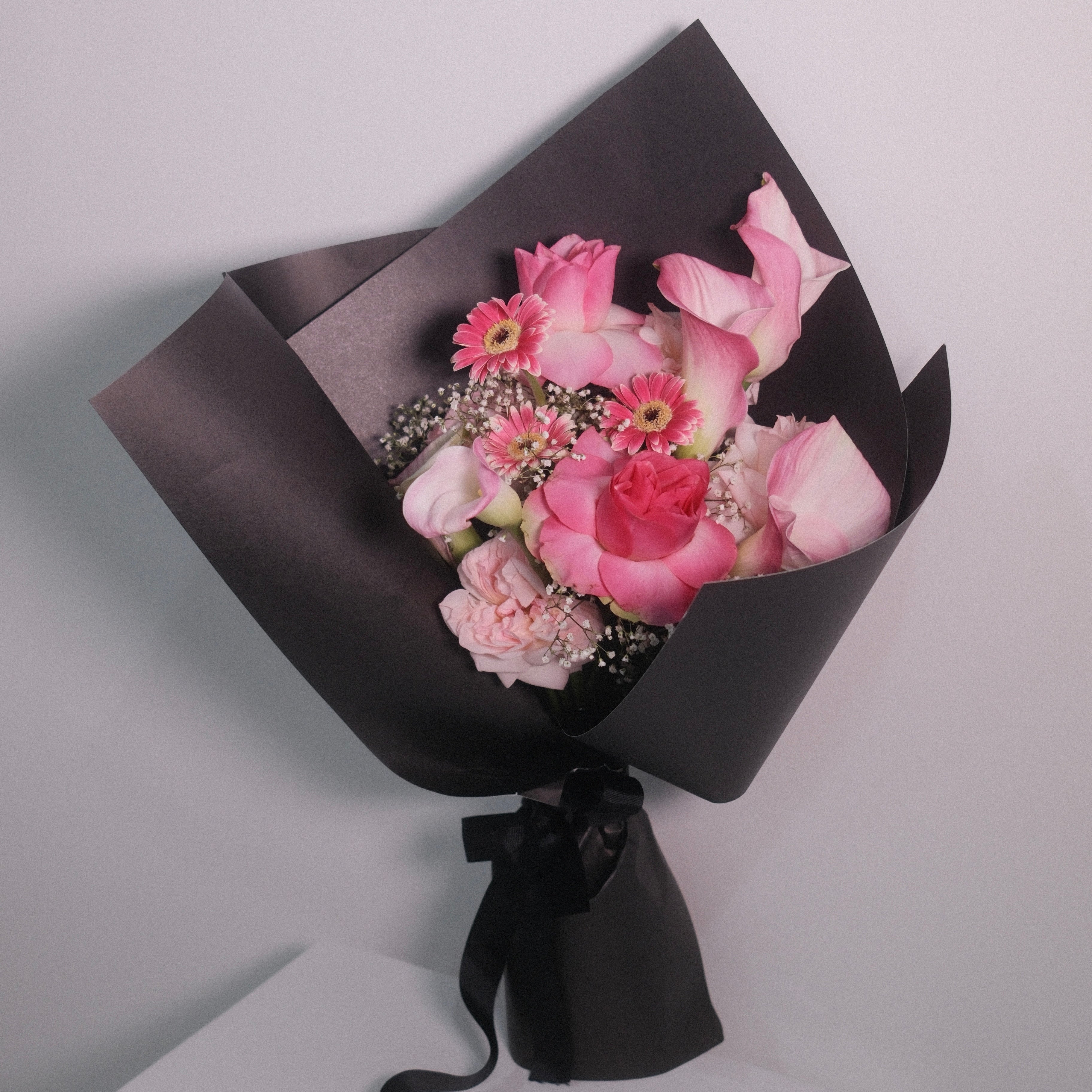 Bouquet of pink roses and calla lilies flowers wrapped in black paper with a black ribbon, Hanaya Flora, Surry Hills, Sydney.