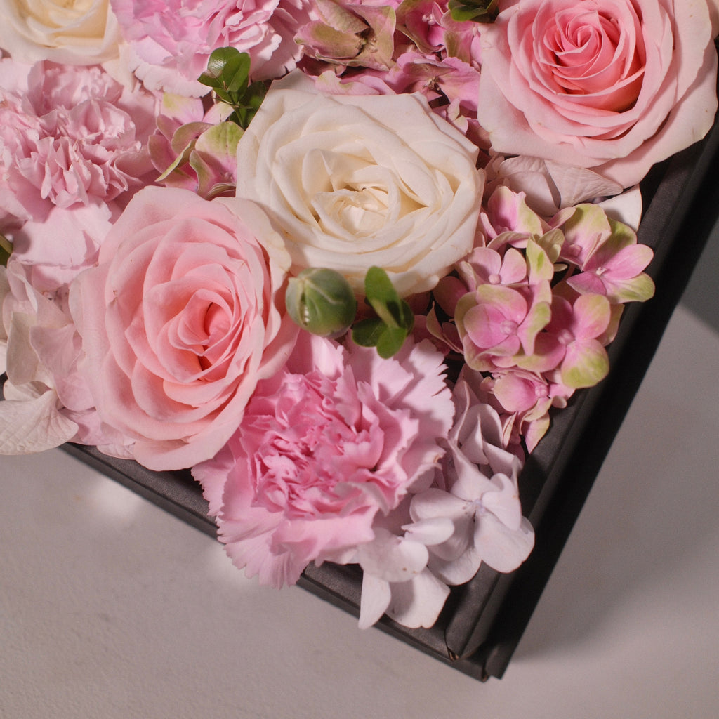 Close-up of the Hanaya Box Pink (B) with pink and white roses in a modern black box
