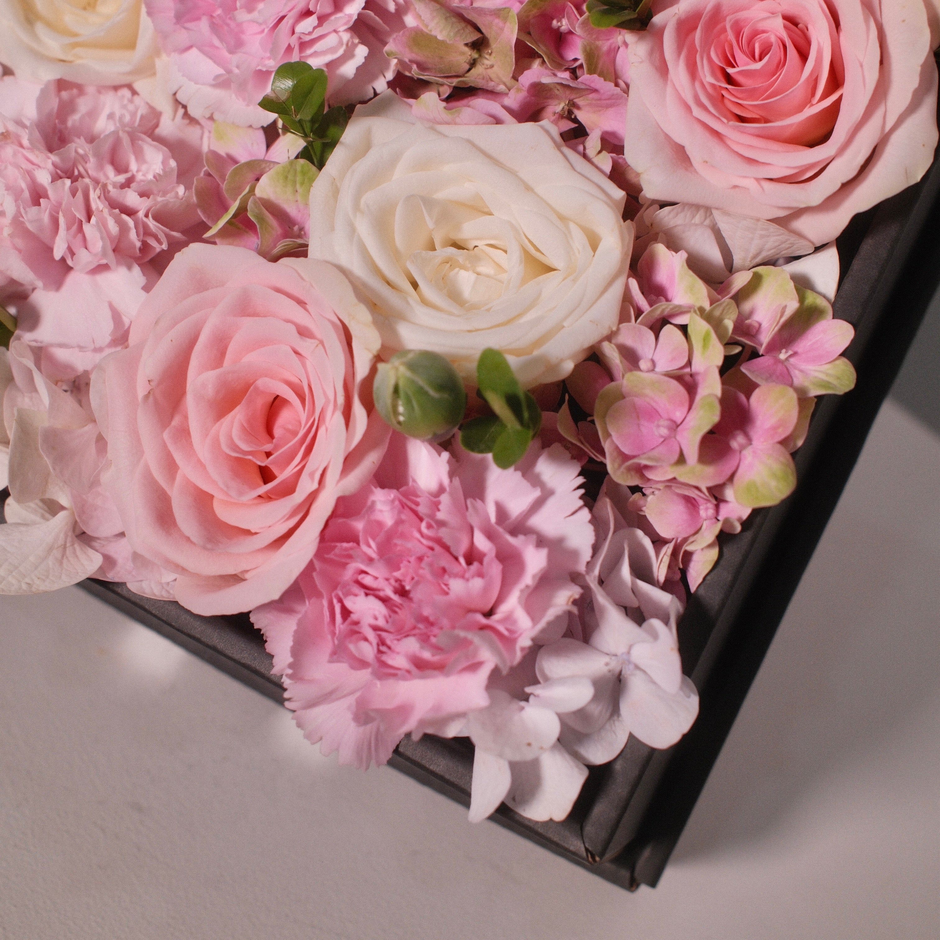 Close-up of the Hanaya Box Pink (B) with pink and white roses in a modern black box