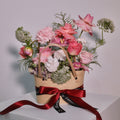Floral arrangement with soft pink roses in a woven basket with a red ribbon by Hanaya Flora, based in Sydney.