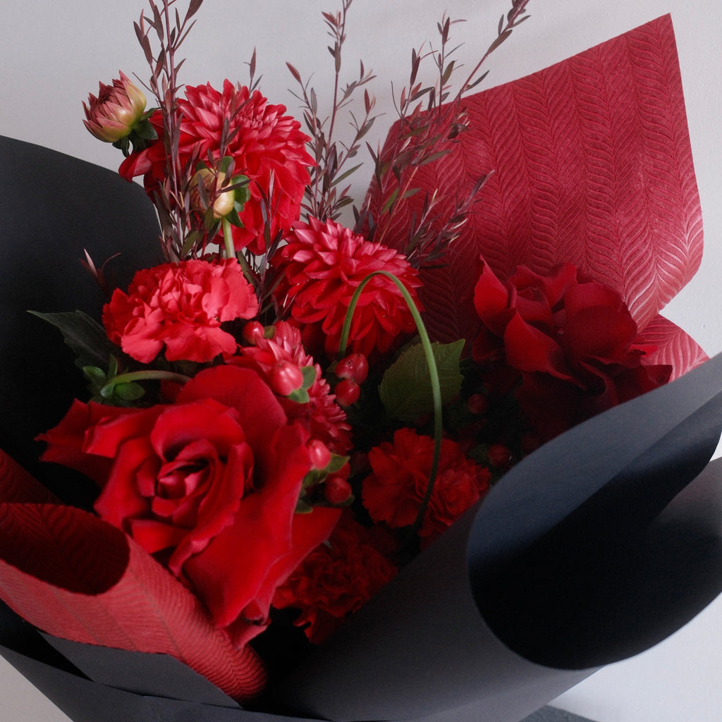 Bouquet of red flowers wrapped in black paper with a red ribbon, perfect for graduation gift ideas made by Hanaya Flora, based in Sydney.