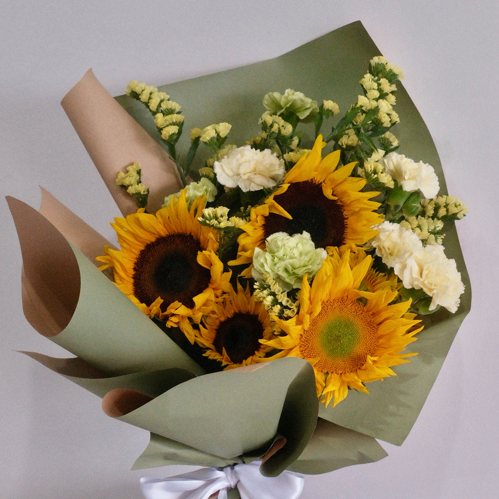 Bouquet of sunflowers and white flowers wrapped in green paper with a white ribbon, perfect for graduation flower gift delivered by Hanaya Flora, based in Sydney.