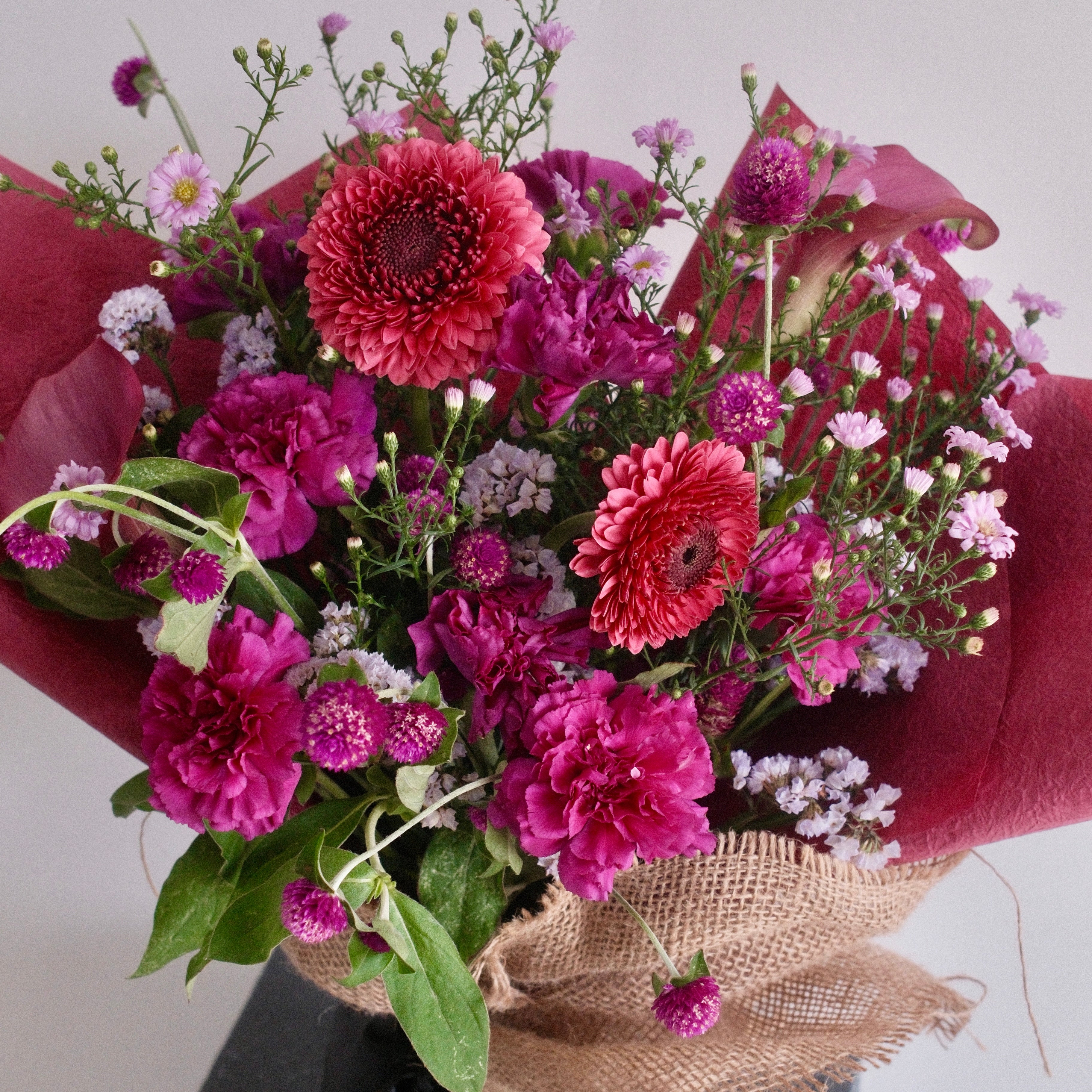 Bouquet of purple flowers wrapped with cerise paper with black ribbon, perfect for celebrating a graduation made by Hanaya Flora, based in Sydney. 