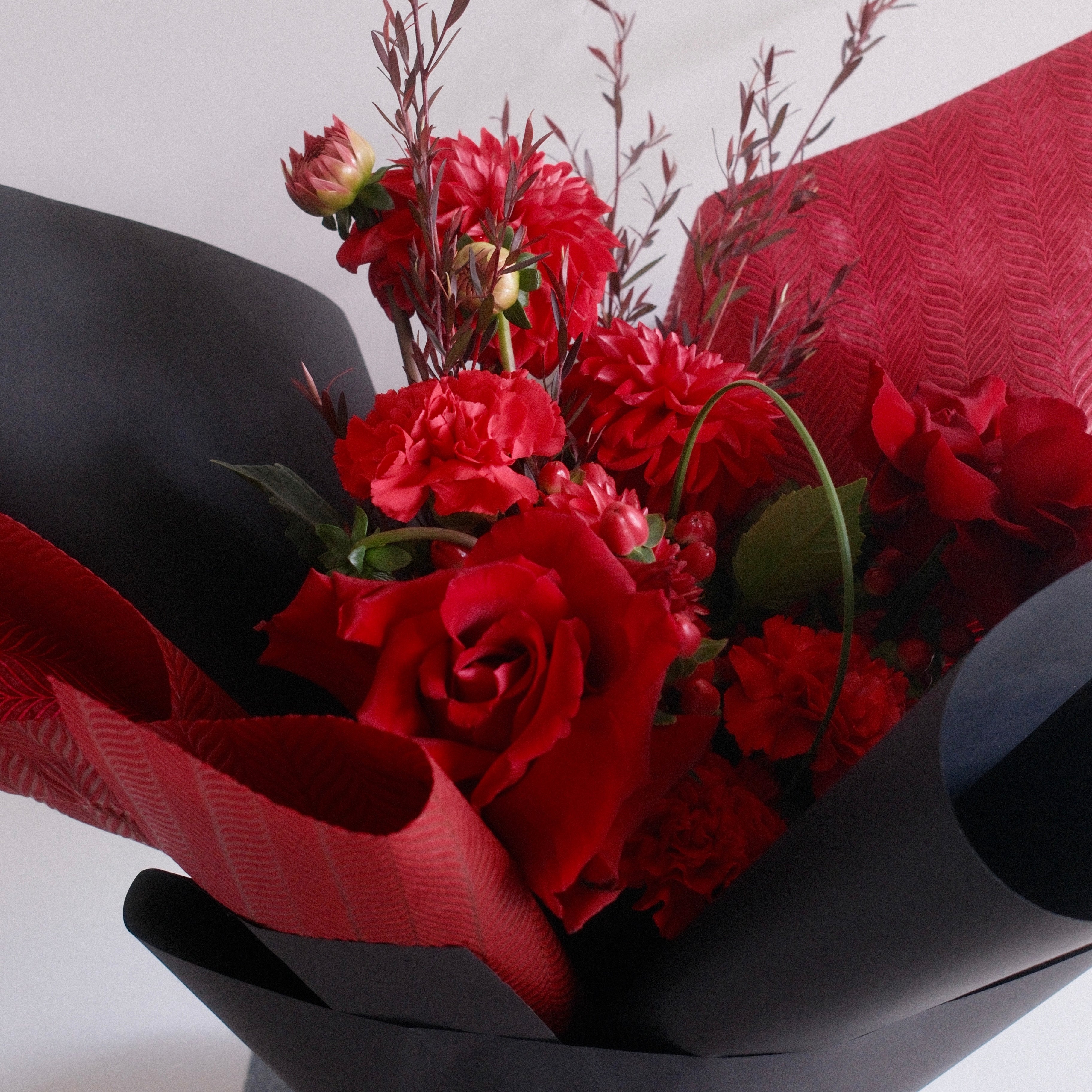 Bouquet of red flowers wrapped in black paper with a red ribbon, perfect for graduation gift ideas made by Hanaya Flora, Surry Hills, Sydney.