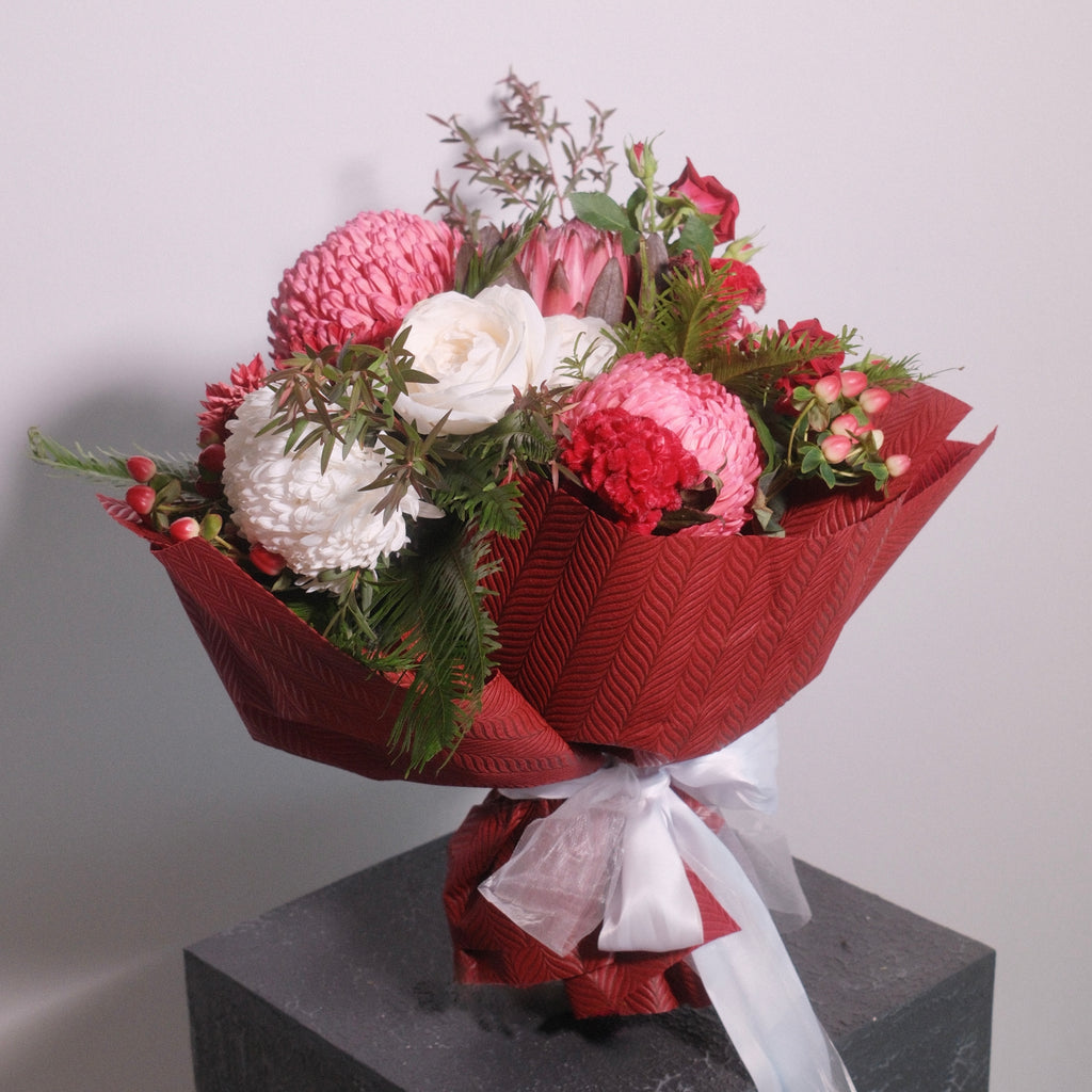Bouquet of flowers roses, chrysanthemum, with red wrap and white ribbon by Hanaya Flora.