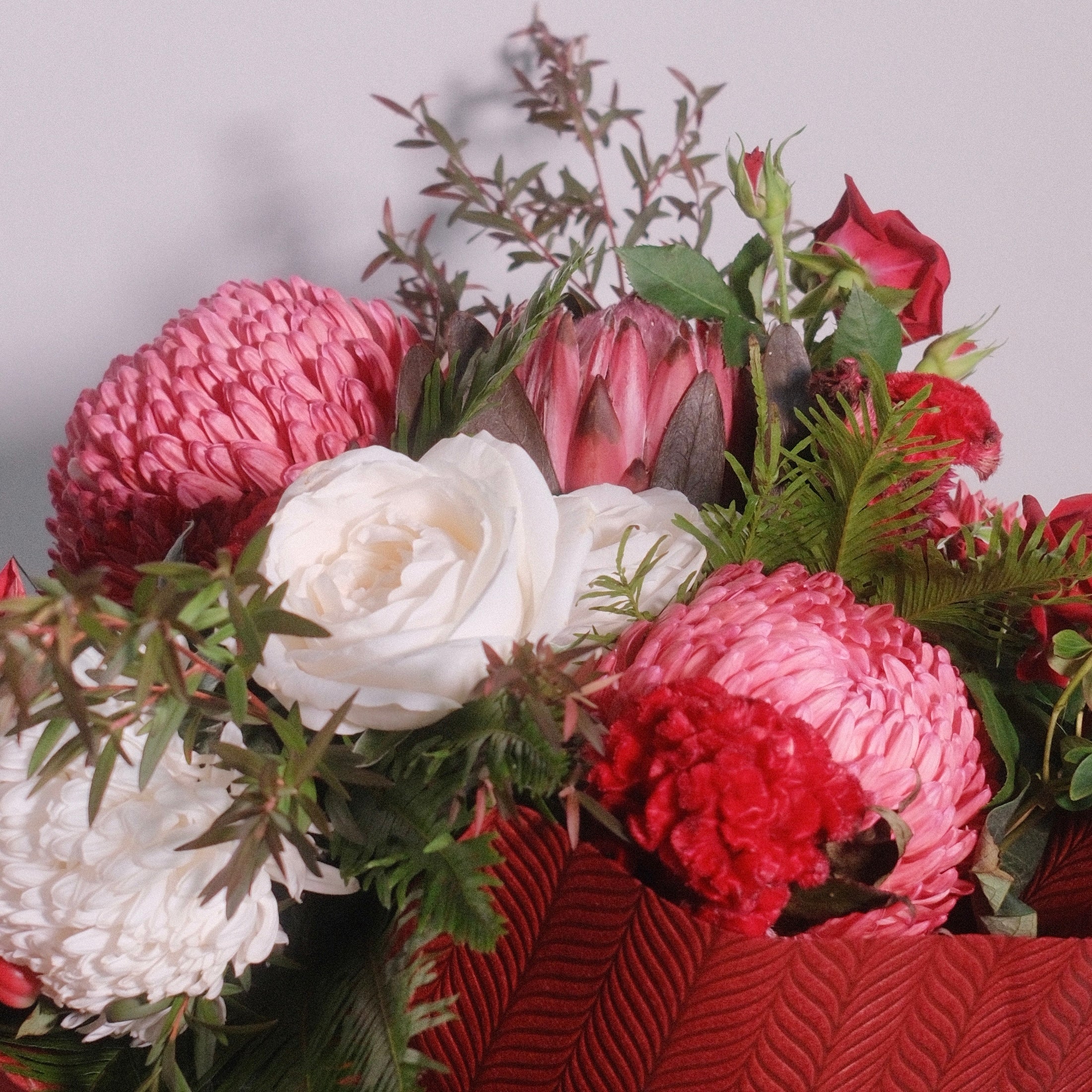 Bouquet of flowers roses, chrysanthemum, with red wrap and white ribbon by Hanaya Flora.