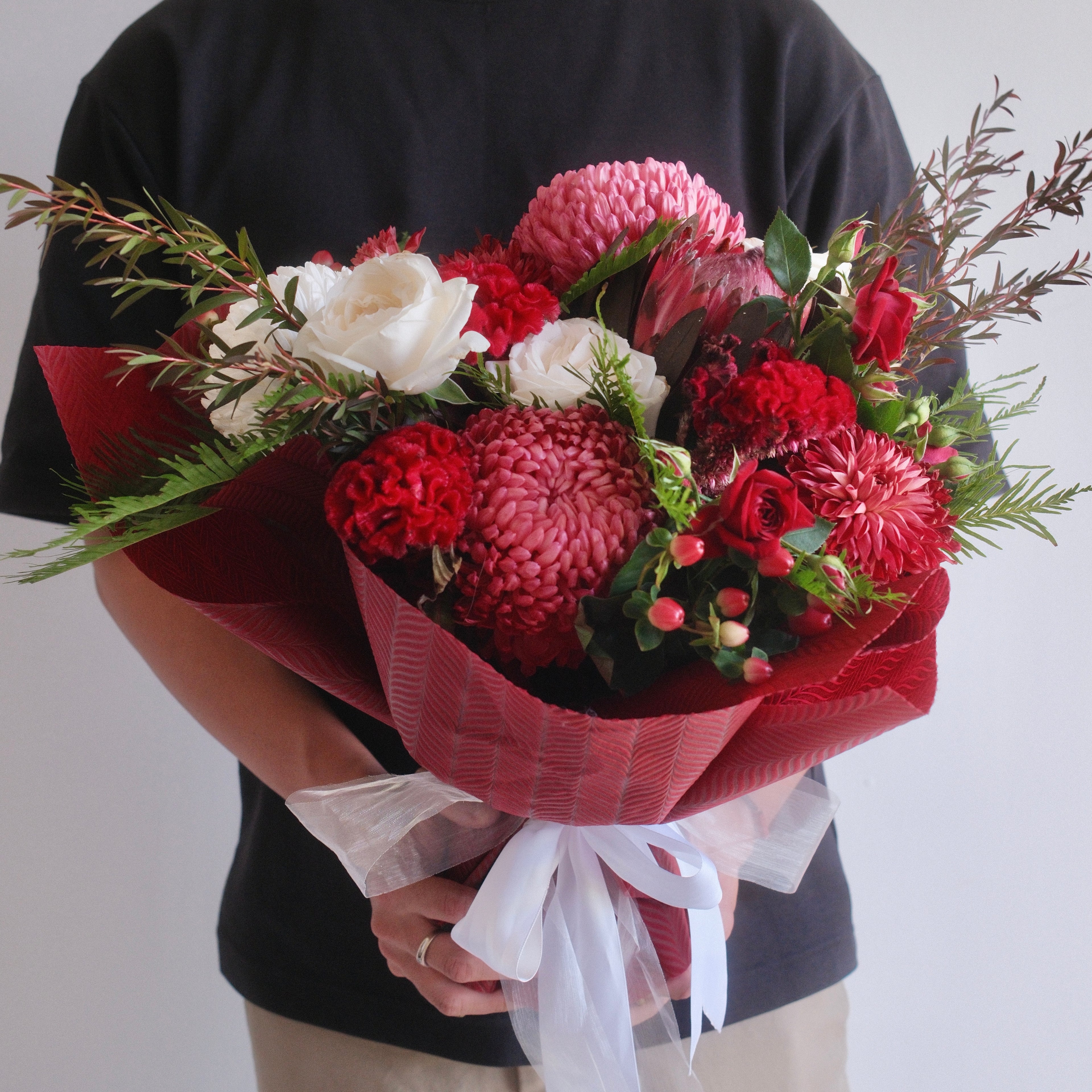 Bouquet of flowers roses, chrysanthemum, with red wrap and white ribbon by Hanaya Flora.