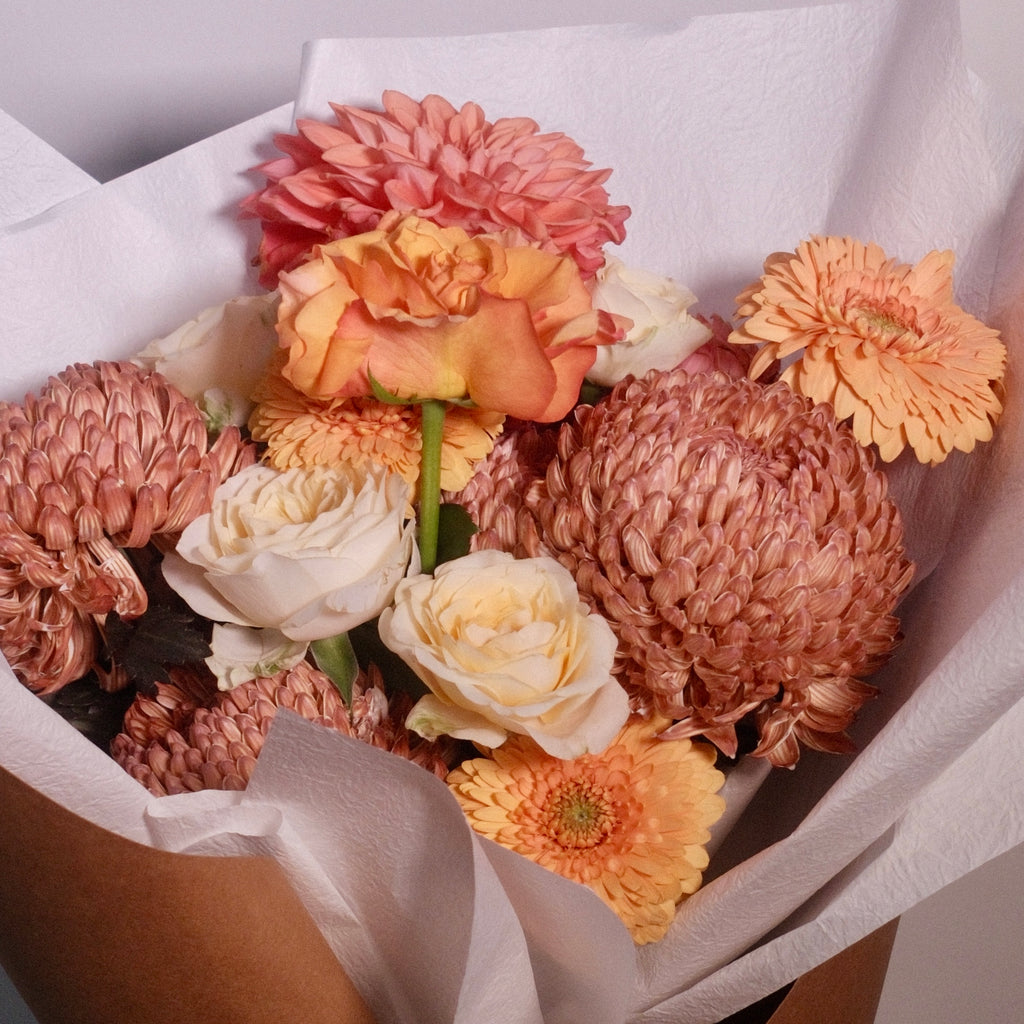Bouquet of brown and yellow rose flowers wrapped in brown paper with a white ribbon. Designed for brown gown for university graduation ceremonies, perfect graduation gift by Hanaya Flora, based in Sydney.