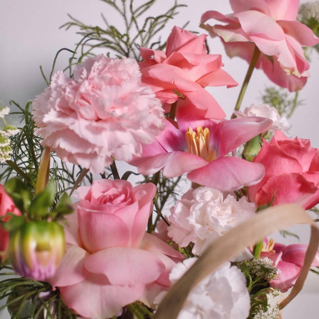 Floral arrangement with soft pink roses in a woven basket with a red ribbon by Hanaya Flora, based in Sydney.