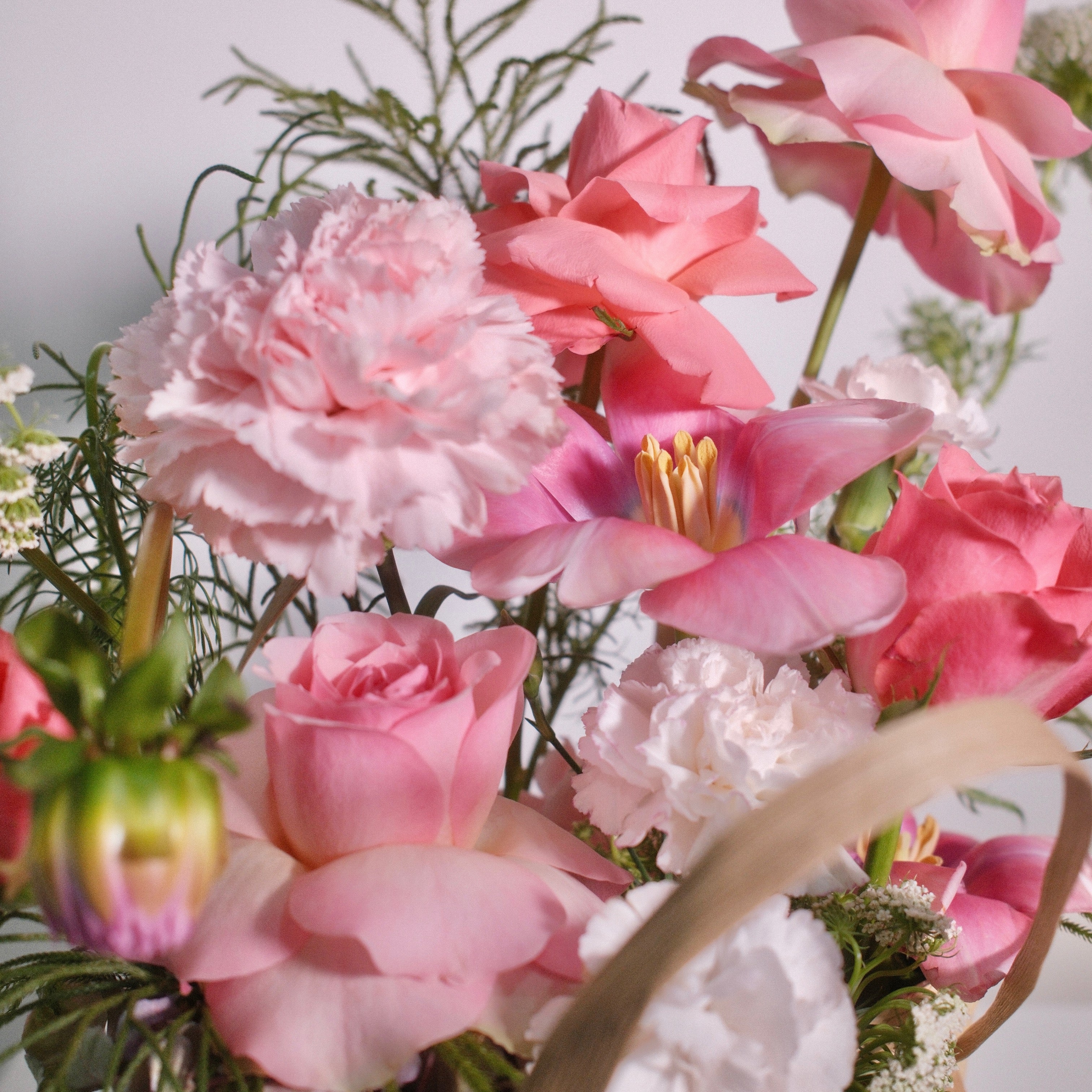 Floral arrangement with soft pink roses in a woven basket with a red ribbon by Hanaya Flora, based in Sydney.