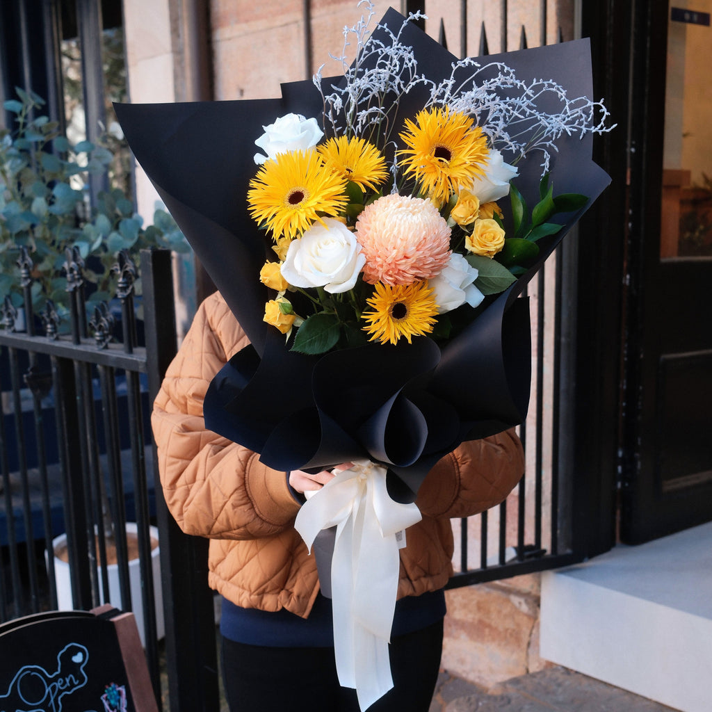 Sunny Wishes get well bouquet with yellow gerbera daisies, peach chrysanthemum and white roses, held by a customer at Hanaya Flora Surry Hills