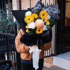 Sunny Wishes get well bouquet with yellow gerbera daisies, peach chrysanthemum and white roses, held by a customer at Hanaya Flora Surry Hills