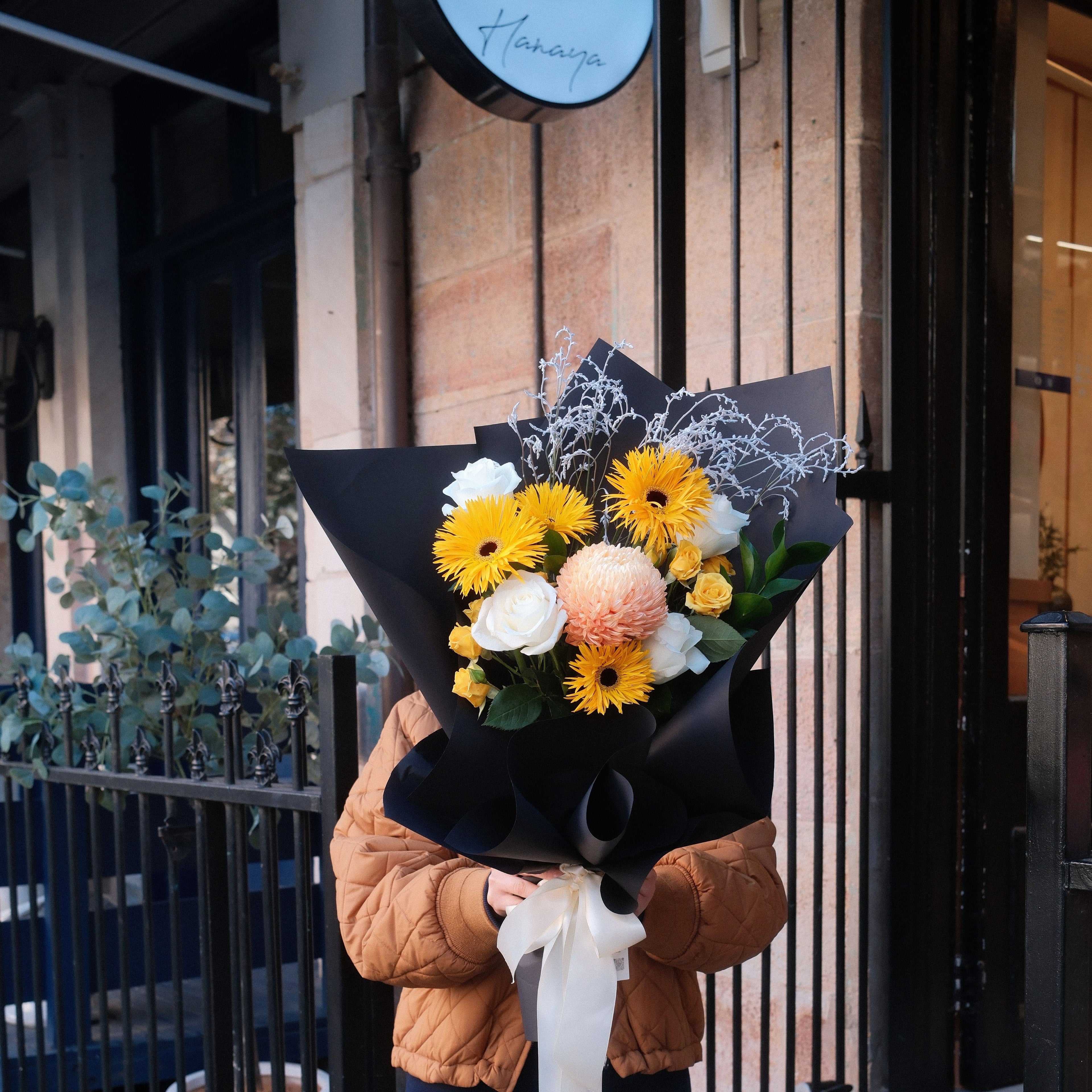 Sunny Wishes bouquet held outside the Hanaya Flora storefront sign in Surry Hills