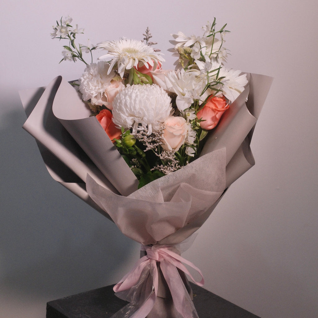 Bouquet of white flowers wrapped in brown paper with a pink ribbon by Hanaya Flora, Sydney. Perfect graduation gift and flowers ideas.
