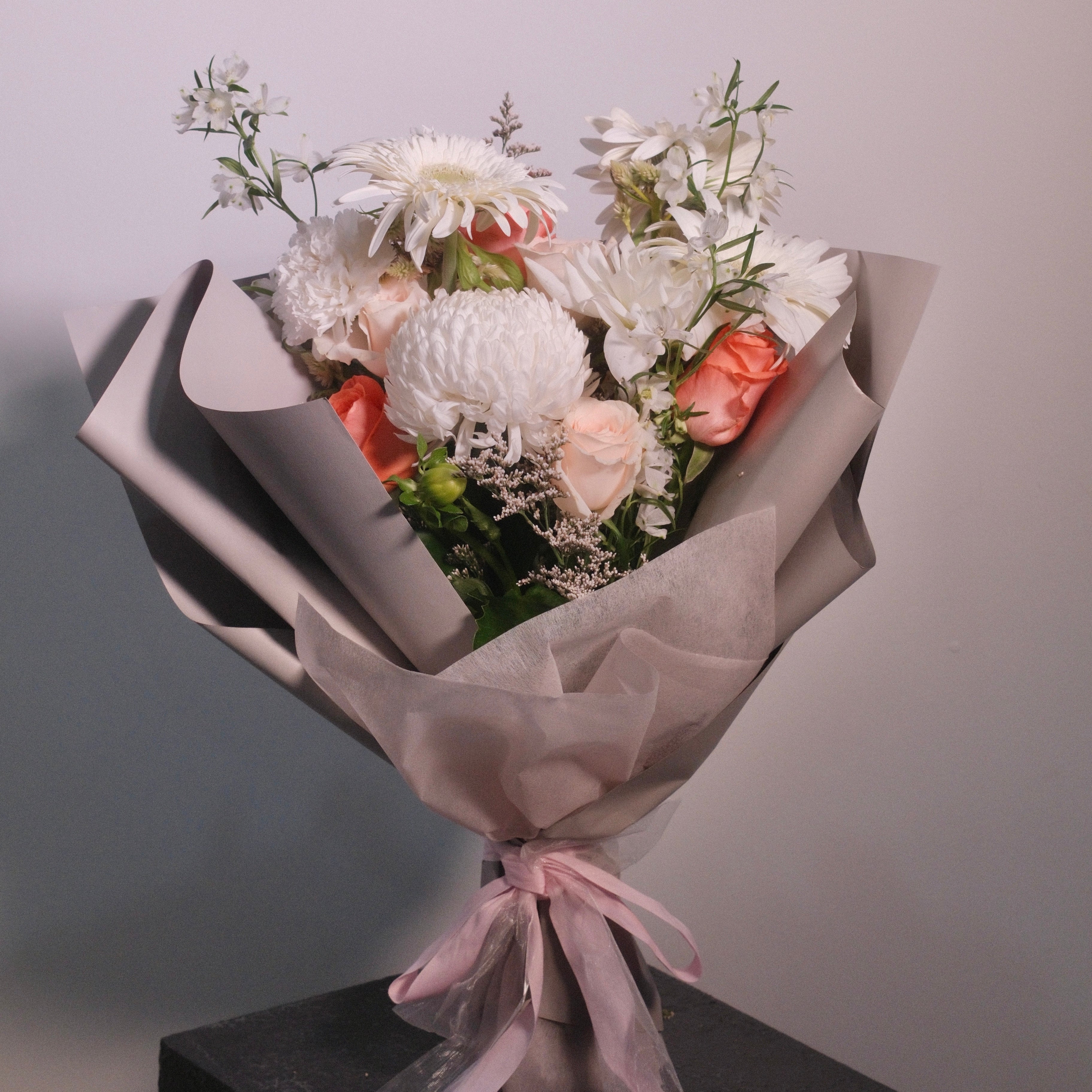 Bouquet of white flowers wrapped in brown paper with a pink ribbon by Hanaya Flora, Sydney. Perfect graduation gift and flowers ideas.