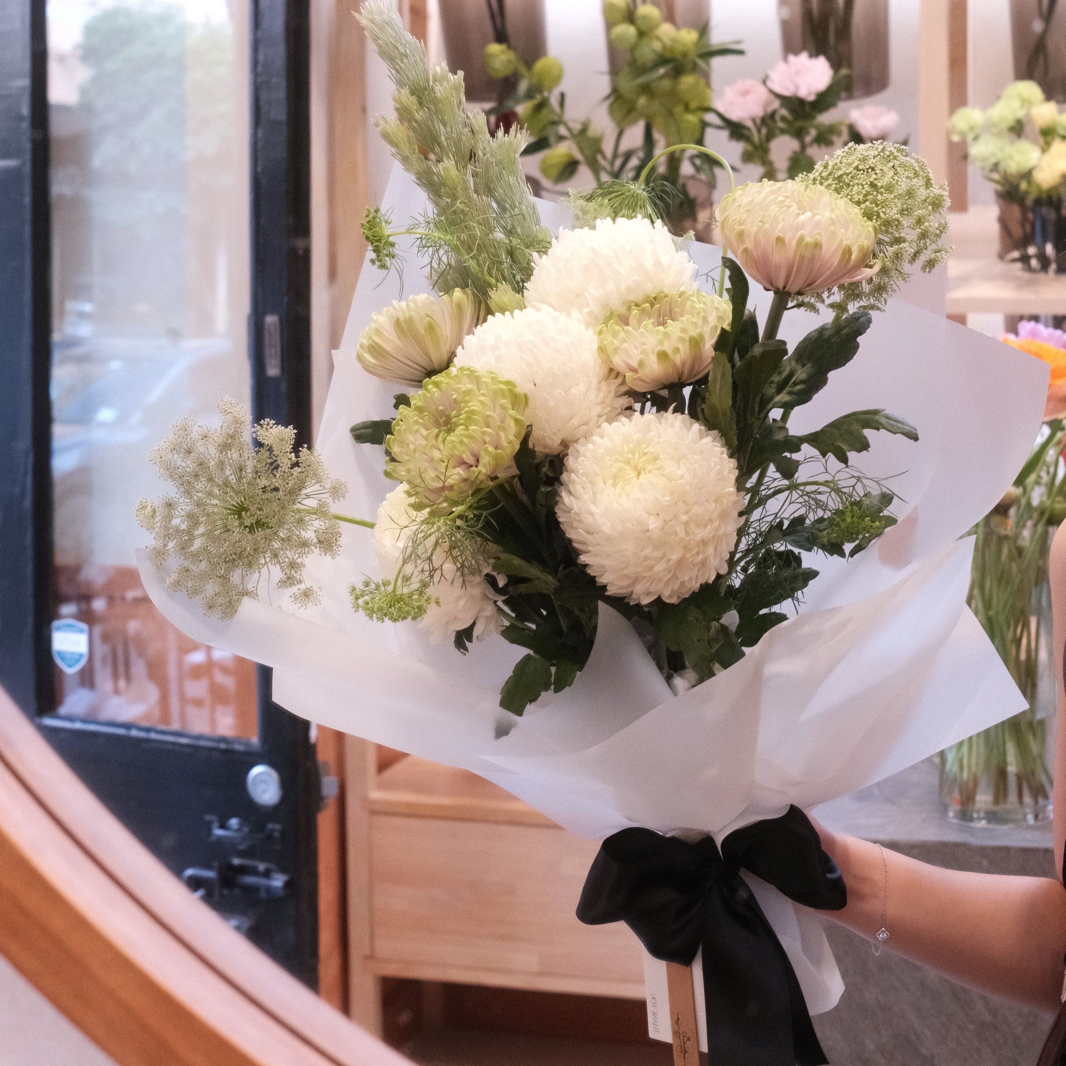 Quiet Comfort bouquet of white chrysanthemums wrapped in white paper with a black ribbon, Hanaya Flora Surry Hills