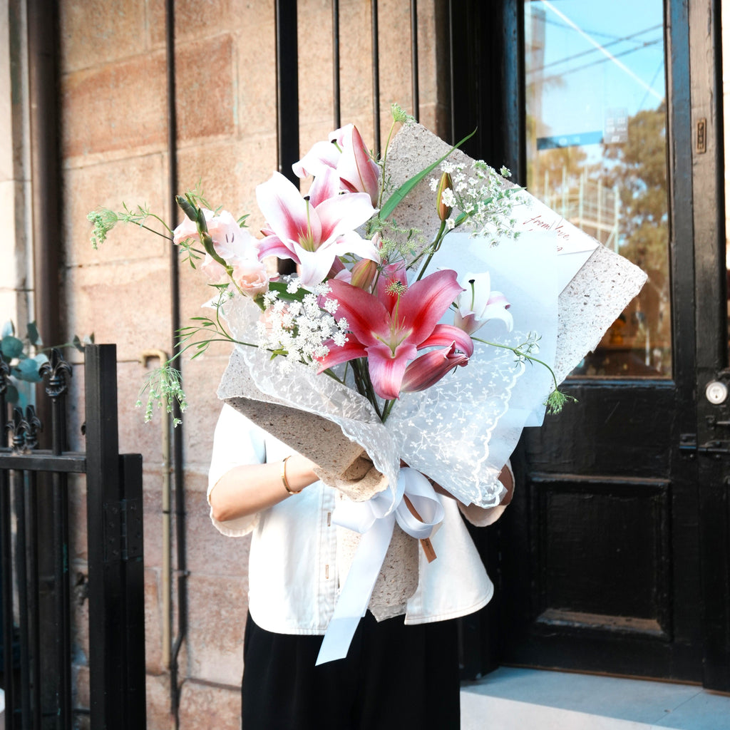 Florist holding the Yuri pink lily bouquet, a May birthday flower gift, Sydney